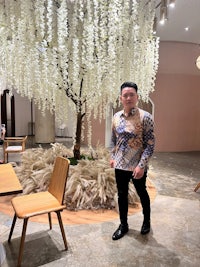 a man standing in front of a white flower tree