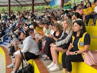 a group of people sitting on bleachers watching a basketball game