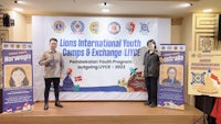 two people standing in front of a banner with the words lions international world games & exchange luv